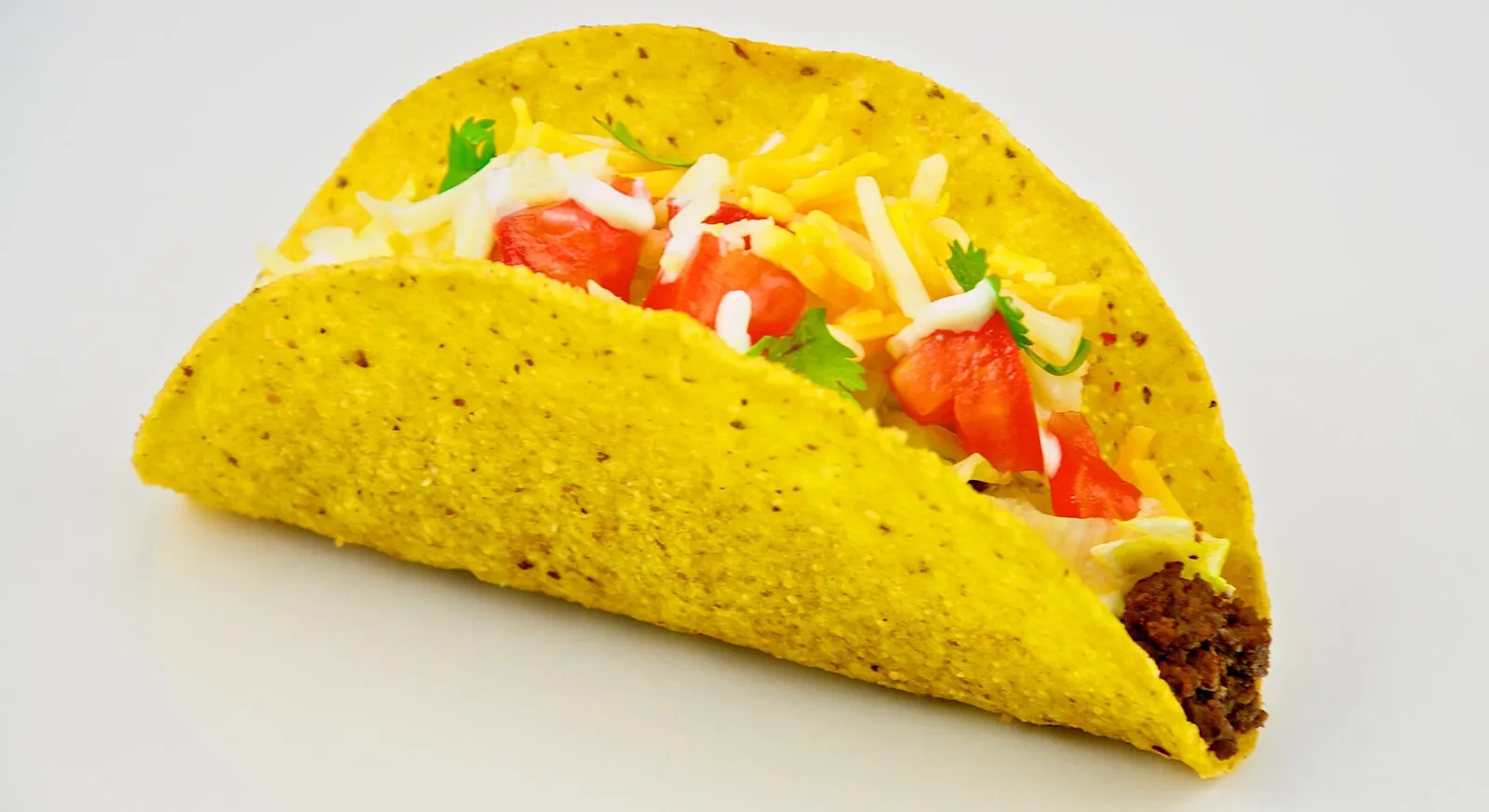 A traditional American hard-shell taco with ground beef, lettuce and tomato