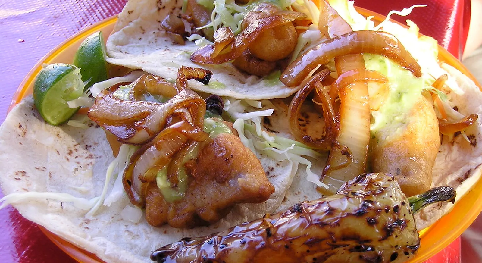 Battered fish tacos with cabbage, crema and lime