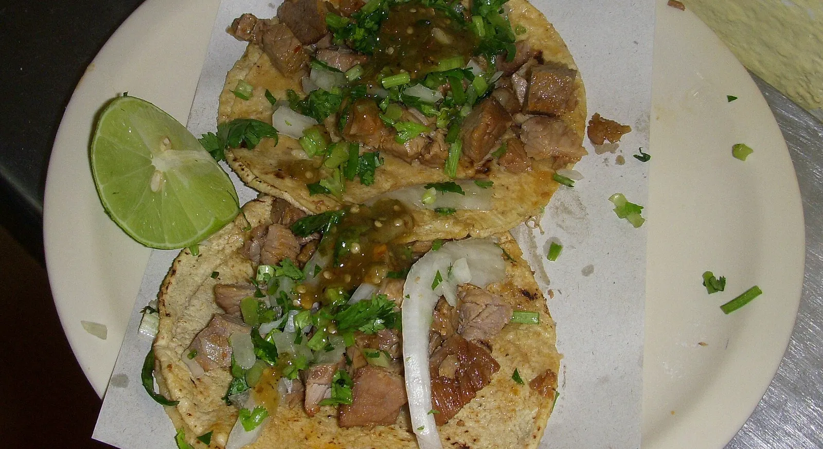 Cabeza tacos on corn tortillas with onion, cilantro and lime wedges