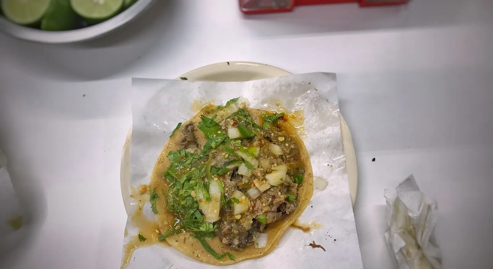 A suadero taco on a corn tortilla with chopped onion and cilantro