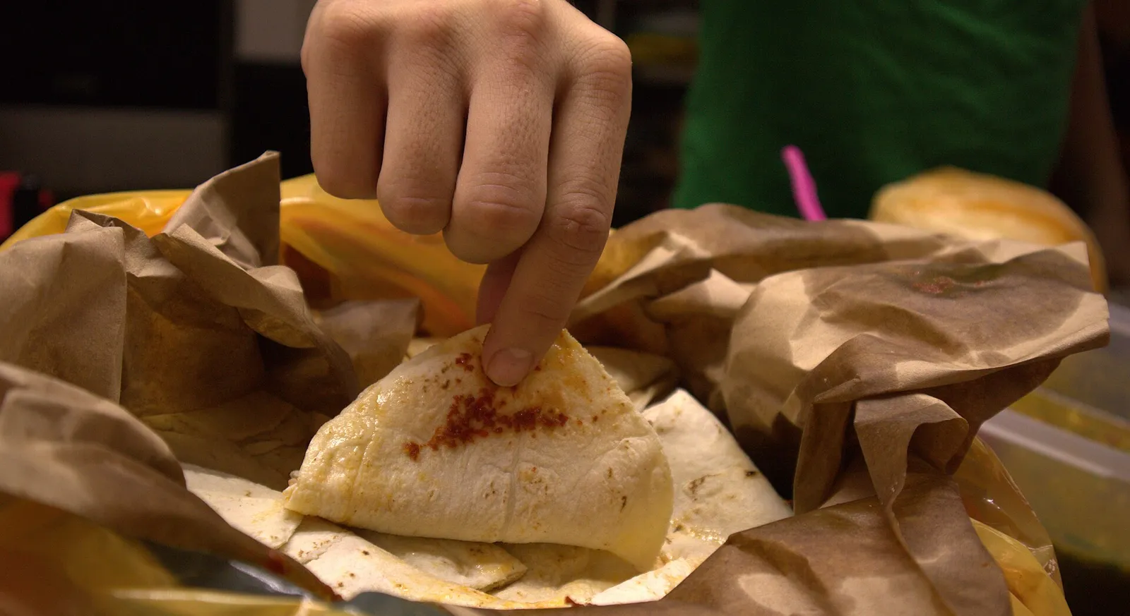 A hand taking a steamed taco de canasta from a cloth-lined basket
