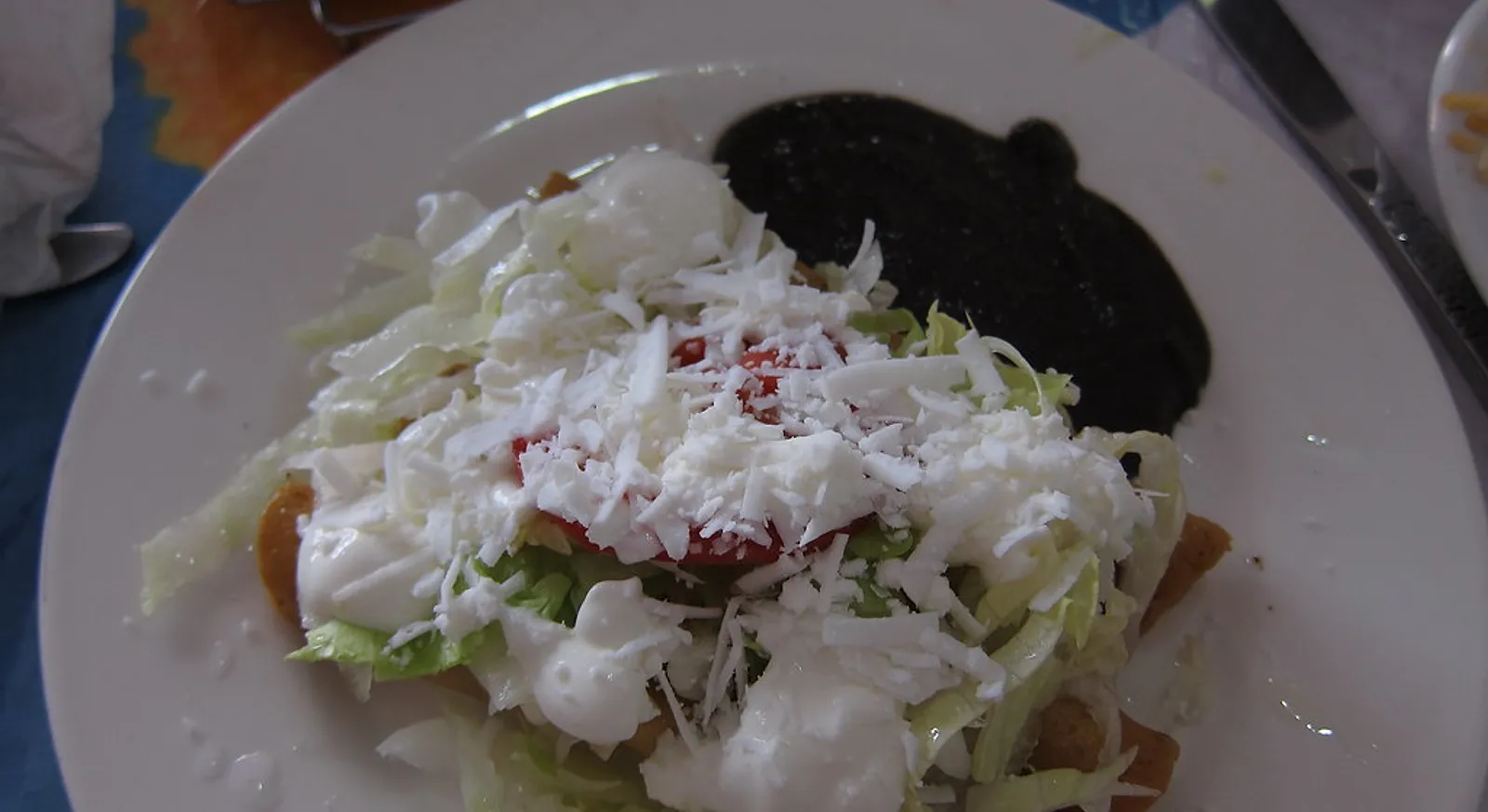 Tacos dorados, crispy fried tacos, topped with lettuce, crema and cheese with a side of beans